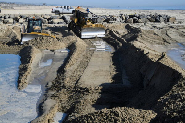 Workers use heavy machinery to make a berm to keep out further oil from coming into the controlled basin after a major oil spill off the coast of California has come ashore in Huntington Beach, California, U.S. October 3, 2021. REUTERS/Gene Blevins